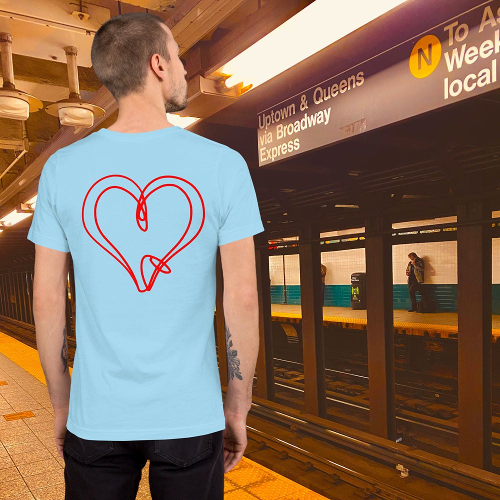 Man at subway station wearing a light blue T-shirt with a red heart knot design on the back.