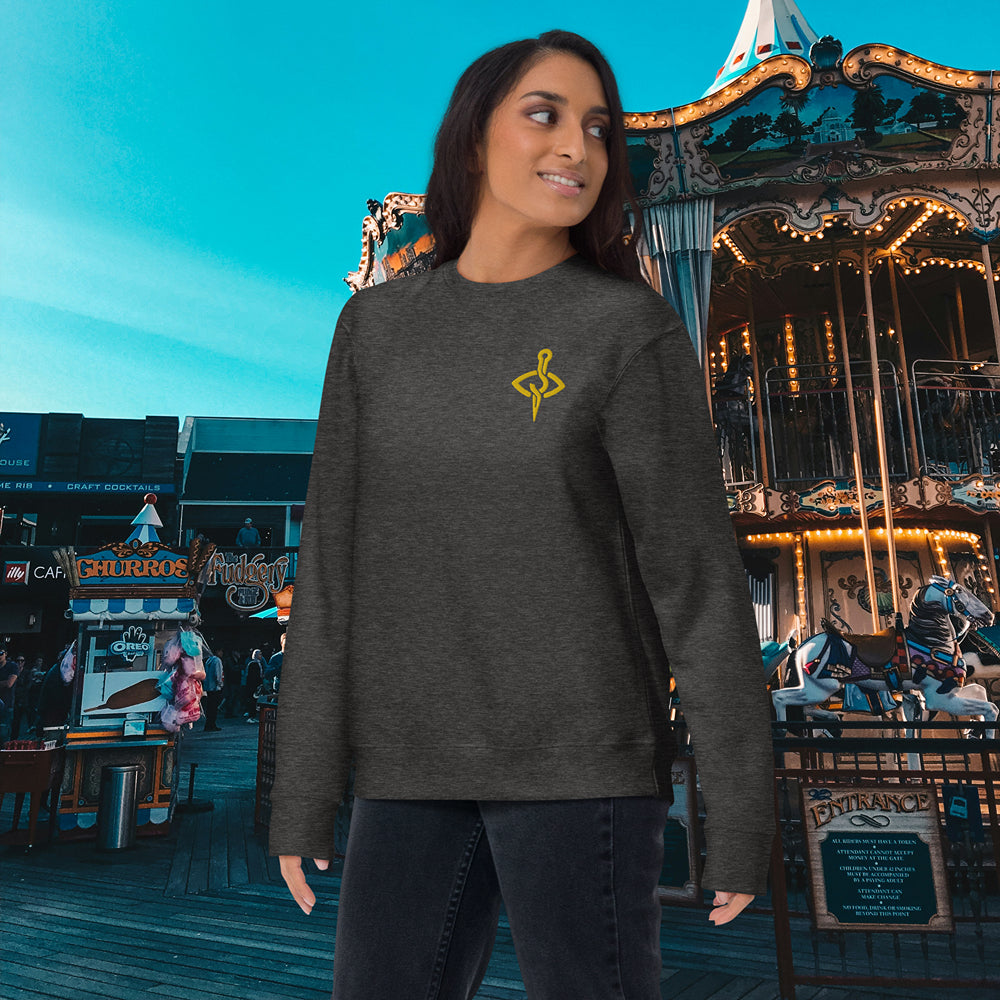 Woman smiling in a charcoal heather sweatshirt with a distinctive golden yellow sewing emblem