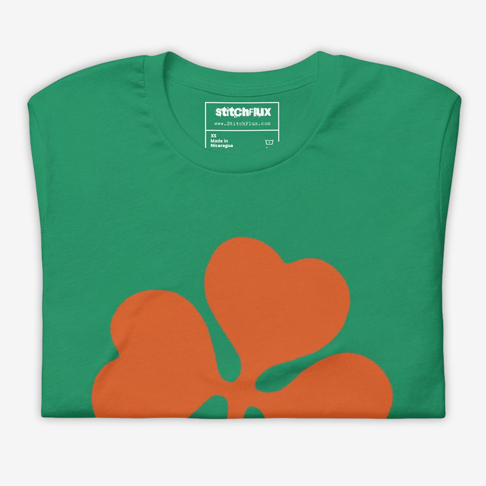 Folded green T-shirt with orange clover design on the front.