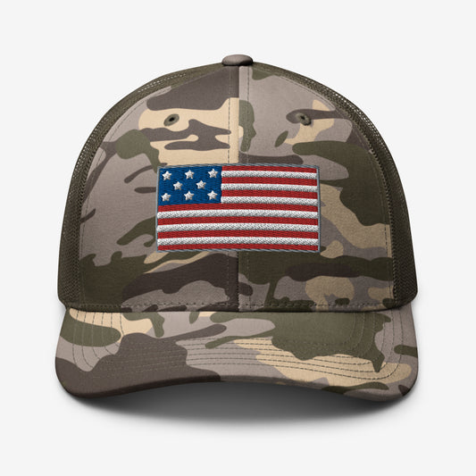 Front view of a camo trucker hat with an American flag patch.