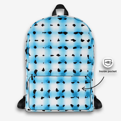 Frontal view of an all-over print backpack, displaying the eye-catching blue and black splatter design, a front utility pocket with zipper, and a black top handle.