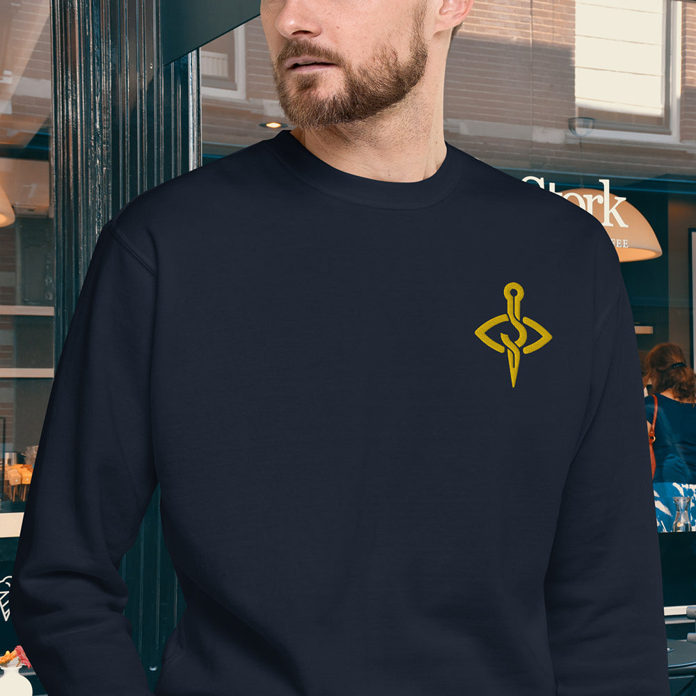 Man wearing a navy sweater with a distinctive golden yellow embroidery design