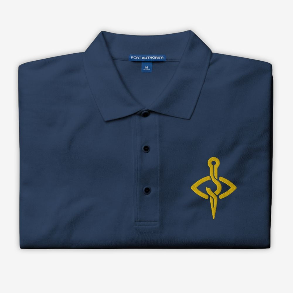 Folded view of a Stitch Art Embroidered Polo in silver with a distinctive needle and thread logo, showcasing a blend of style and craftsmanship.